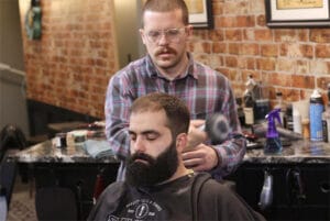 Taylor Horsman, a barber at Saving Face in Manlius. cutting the hair of one of his clients.
